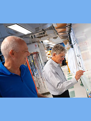 Professor David Kleinfeld works at a white board in his lab.